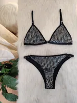 Conjunto de bikini negro con aplicaciones plateadas. El corpiño es de corte triangular con tirantes finos regulables y la bombacha es tipo colaless con laterales regulables.