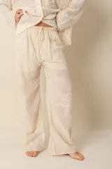 Pantalón ancho color crema con bordados florales, 100% algodón, cintura con elástico y detalle en crochet en la cintura.