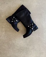 Bota de cuero color marrón con caña alta, hebillas y arnés.