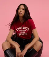 Remera baby look roja de algodón con estampa frontal con la frase "Chill Vibes California Season Sporty" en color blanco.