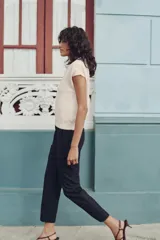 Pantalón largo negro con finas rayas verticales blancas, de tiro alto y corte recto.
