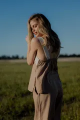 Conjunto de top y pantalón color beige. El top es de breteles anchos, con escote cuadrado y detalle de bordado en el frente. El pantalón es de corte recto y ancho, con bolsillos laterales y cintura con elástico y botones.