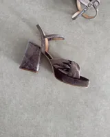 Sandalia de cuero vacuno color dorado, con plataforma y taco cuadrado. Presenta una tira delgada en el tobillo y detalle de nudo en la capellada.