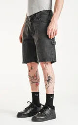 Bermuda de denim negro con calce oversize, estilo carpintero y bolsillo lateral.
