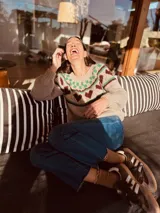 Sweater de punto color gris con diseño de corazones rosas y cuello con diseño geométrico.