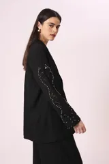 Blazer negro con mangas de encaje bordado y solapas clásicas.