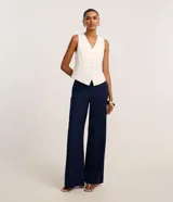 Pantalón de vestir azul marino, de corte amplio, con cintura alta, cinturón incorporado y cierre delantero.