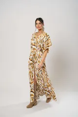 Vestido largo con estampado animal print en tonos camel, blanco y negro. Tiene escote en V, mangas cortas tipo murciélago y tajo frontal. Incluye cinturón ancho de cuero color camel.