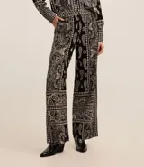 Pantalón largo de corte ancho con estampado paisley en tonos blanco y negro. Presenta cintura alta con trabillas, cierre frontal tradicional y confección en tejido viscolino, una mezcla de lino y viscosa.