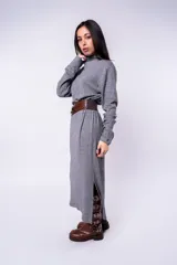 Vestido midi gris de punto, con cuello alto y mangas largas. Incluye cinturón ancho de cuero marrón con hebilla metálica.