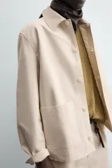 Sobrecamisa color beige de algodón con estructura canvas, corte relaxed fit, cuello solapa, manga larga con puño abotonado, bolsillos de plastrón frontales y cierre frontal con botones.