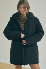 Anorak negro resistente al agua y al viento con aislamiento térmico, cuello alto con capucha ajustable, mangas largas con puño interior de neopreno, tirantes elásticos interiores, bolsillos delanteros con forro polar y cierre de cremallera, bolsillo interior con cremallera oculta y cierre frontal con cremallera termosellada.