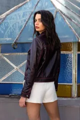 Campera corta de cuero ovino color borgoña, estilo jeanera, con cuello clásico, bolsillos con solapa y cierre frontal con broches metálicos.