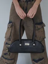 Cartera tipo baguette de cuero sintético negro con textura de reptil. Tiene doble asa corta, cierre superior y logo metálico plateado de la marca en el frente.