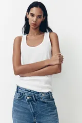Pantalón de jean celeste de tiro alto, corte wide leg y largo hasta el tobillo. Presenta un diseño asimétrico en la cintura con cierre frontal cruzado con cremallera y botones metálicos.