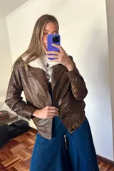 Campera bomber de cuero marrón veteado con cuello desmontable de corderito crudo y detalle de pasamanería en las mangas.