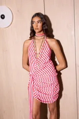 Vestido corto de gasa con estampado de rayas verticales rojas y blancas. Posee un escote pronunciado, espalda descubierta y detalle de drapeado lateral con un lazo largo multifuncional.