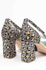 Zapato de tacón con estampado animal print gris y dorado, con puntera fina, talón descubierto y pulsera con hebilla lateral. Tacón ancho de 7 cm y suela de cuero.