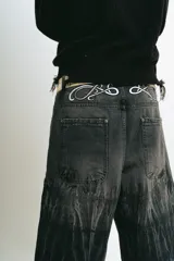 Bermuda de jean negro con lavado ácido gris, corte baggy y bolsillos grandes. Presenta bordados plateados y blancos, cierres y botón personalizado.