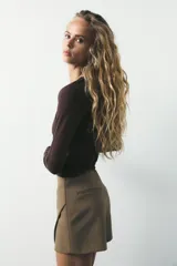 Falda pantalón color beige de tiro medio con diseño asimétrico.