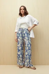 Pantalón ancho de tela liviana con estampado de hojas color crema sobre fondo azul. Tiene cintura elastizada con lazo ajustable.