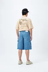 Bermuda carpenter de denim negro, corte relajado y largo a la rodilla, con costuras visibles y múltiples bolsillos funcionales.