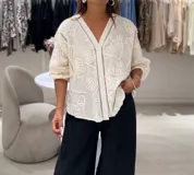 Camisa blanca de manga larga con puños elásticos, cierre frontal con botones y apliques bordados de flores en la parte delantera y trasera.