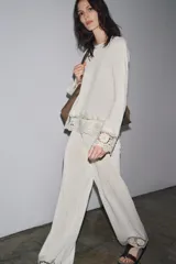 Camiseta blanca de manga larga con cuello redondo y detalle de encaje en el ruedo y puños.