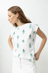 Blusa blanca de mangas cortas con bordado floral en el frente.
