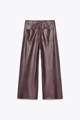Pantalón marrón de tiro alto con efecto cuero, bolsillos de parche en la parte trasera y costuras marcadas en la parte delantera. Cierre frontal con cremallera y gancho metálico.