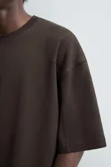 Camiseta negra de corte cuadrado (boxy fit), cuello redondo y mangas cortas. Detalle de costuras en delantero y espalda.