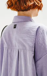 Camisa de manga corta color lavanda con doble bolsillo y ojal delantero con solapa en uno de ellos. Tiene calce oversize y está realizada en tejido plano suave al tacto.
