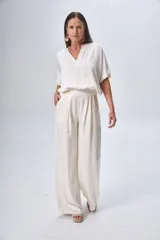 Pantalón palazzo en seda viscosa color crudo, con cintura elástica y caídas fluidas.