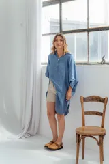 Vestido blanco de lino, corte holgado, con cuello camisero, mangas 3/4 y aberturas laterales.