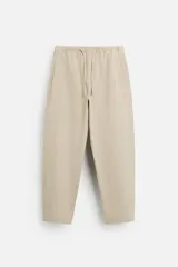 Pantalón de hombre color beige, corte carrot fit, con cintura elástica ajustable con cordón, bolsillos frontales y bolsillo trasero de plastrón.