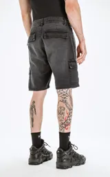 Bermuda de denim negra con corte a la rodilla, estilo cargo con bolsillos laterales y traseros con solapa. Diseño clásico de cinco bolsillos y ruedo desflecado. Confeccionada en denim rígido 100% algodón.