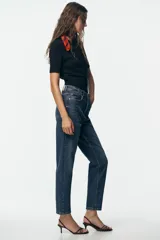 Pantalón de jean negro de corte recto, tiro alto y largo tobillero.