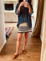 Minifalda tejida en hilo de algodón color arena con rayas horizontales en azul marino y flecos en el ruedo.