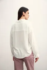 Camisa blanca de mangas largas con detalles bordados y cuello clásico.