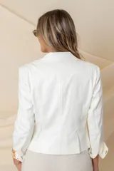 Chaqueta blanca de cuero vegano con corte entallado, cuello solapa, cierre asimétrico con cremallera metálica dorada y mangas 3/4 con puños estampados.