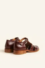Sandalia marrón de cuero vacuno con diseño de tiras entrecruzadas, hebilla lateral y taco bajo de 2,5 cm.