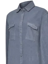 Camisa azul de cotelé de algodón orgánico, con calce holgado, cuello camisero, cierre de botones a presión, mangas largas y dos bolsillos de parche con solapa en el pecho.
