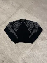 Sweater negro con cuello redondo y diseño geométrico en gris en la parte superior del pecho y hombros.
