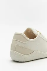 Zapatillas de cuero color blanco y beige, de diseño minimalista con suela marrón.