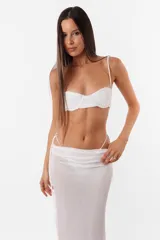 Conjunto de top y falda larga confeccionado en tela con brillos color gris. El top cuenta con arco metálico en el busto, tiras finas para atar en el hombro y ganchos lenceros en la espalda. La falda tiene tiras largas para atar de forma que queden a la vista.