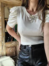 Blusa color crema de lurex con cuello redondo y mangas cortas abullonadas.