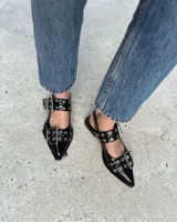 Zapatos negros tipo slingback, con punta fina, dos tiras con hebillas y apliques metálicos.