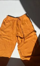 Pantalón de mujer color naranja, de corte palazzo y cintura alta con cordón ajustable.