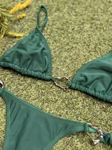 Conjunto de bikini verde con corpiño triangular con argolla metálica en el centro y bombacha colaless con tiras para atar y argollas en los costados.