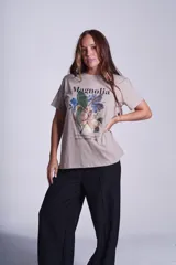 Remera color borgoña de corte recto y cuello redondo, con estampado de una flor de magnolia y texto en blanco.